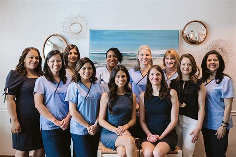 Friendly dental practice team in coordinated navy and light-blue scrubs and dresses