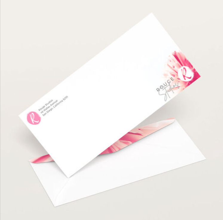 White business envelope with a pink flower graphic and logo in the corner and a printed inside flap