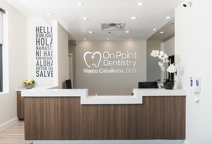 Modern, welcoming dental office reception area with friendly staff in matching branded scrubs