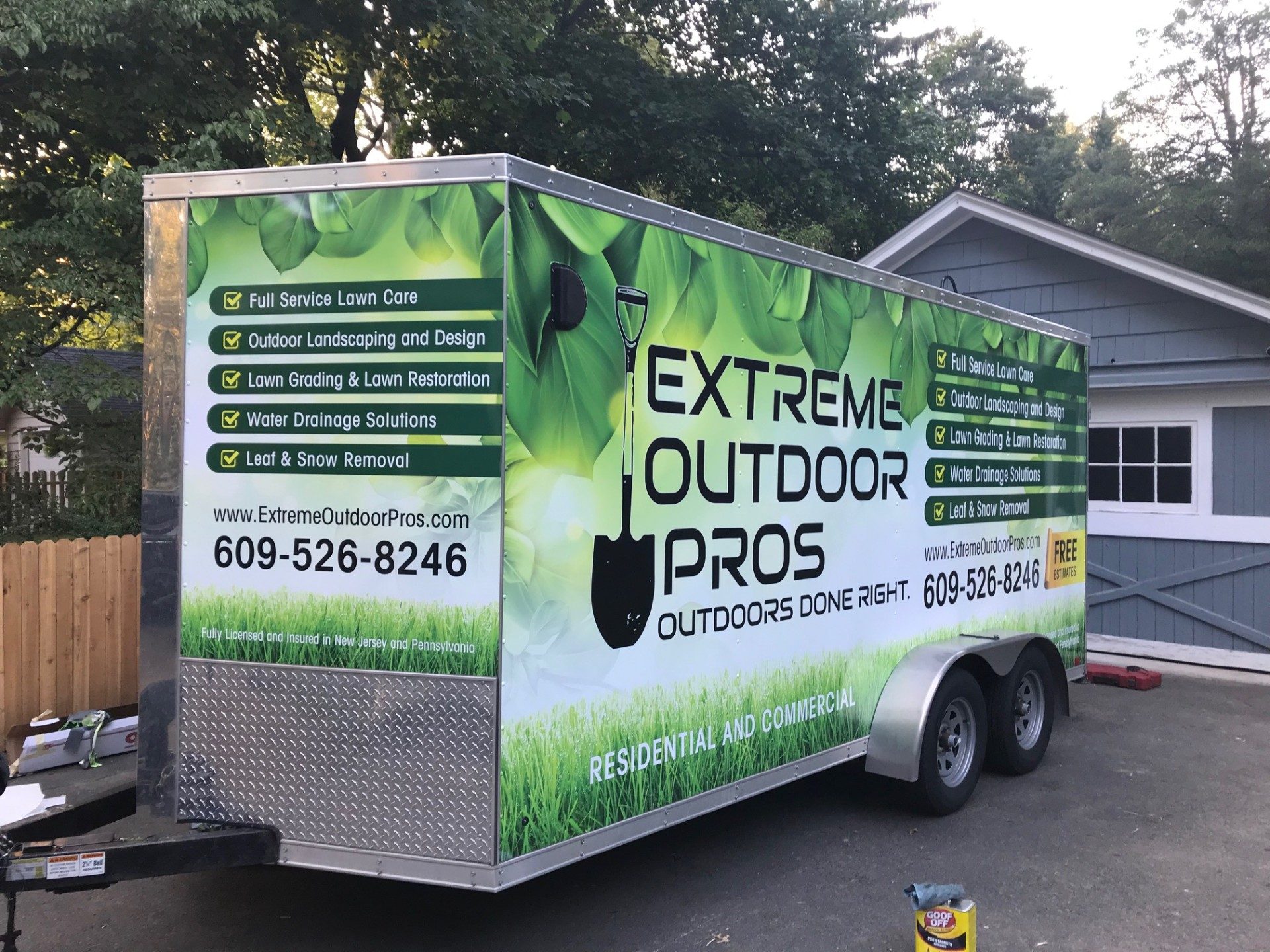 Fully wrapped landscaping company trailer with full-color branding, services list and contact info